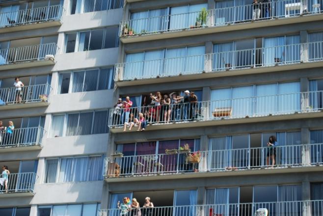 パレードをマンションのベランダから見る人々